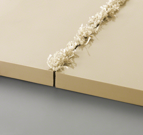 兩塊米色板材，邊緣有新切出的凹槽和捲曲的木屑。