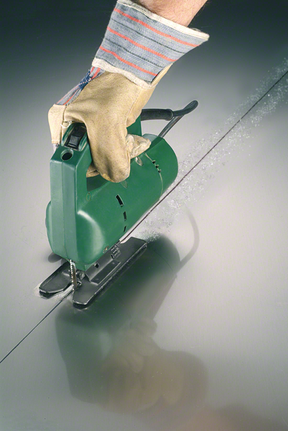 配戴安全設備的人使用曲線鋸在金屬上切割出一條直線。.