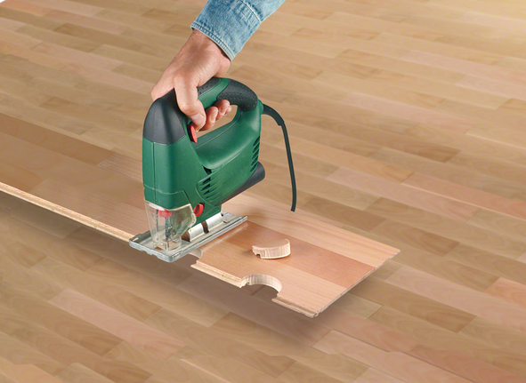 一個人用曲線鋸在木板上切出一個圓形凹口。.