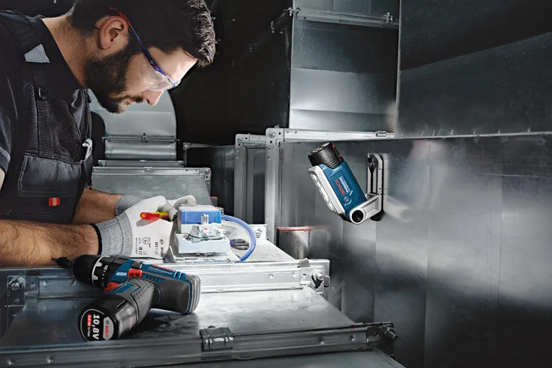 一名配戴安全設備的人員在無線工作燈下操作電線。.