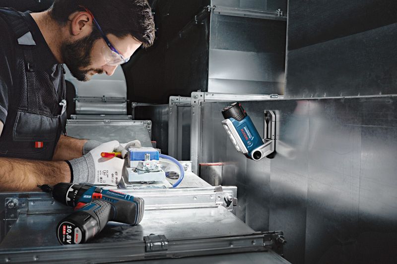 一名配戴安全設備的人員在無線工作燈下操作電線。.