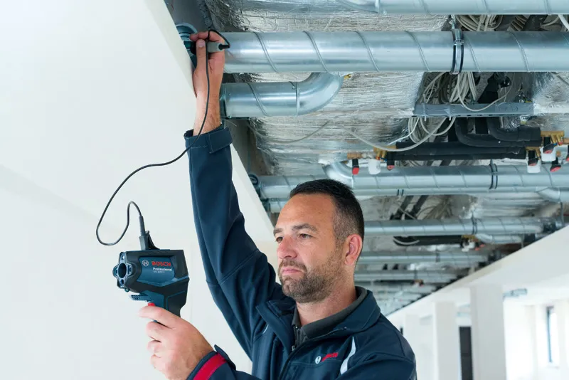 一個人使用檢查攝影機檢查天花板上的通風管道。