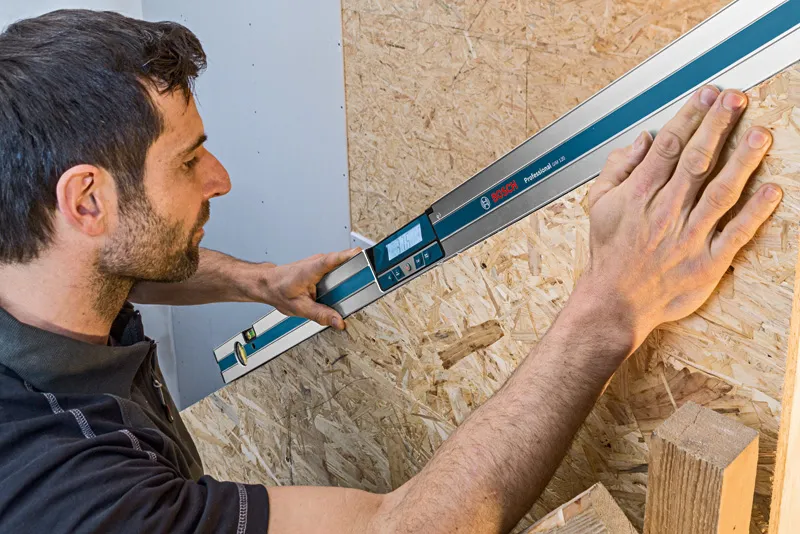 人員使用數位測斜儀測量木質表面的角度。.