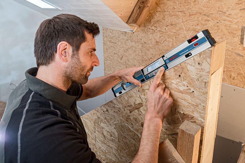 人員使用數位測斜儀測量傾斜的木質表面。.