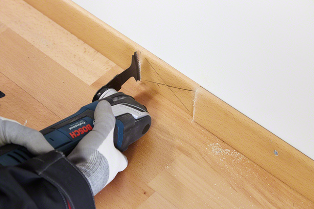 HCS 鉸鏈式切削鋸片 AII 65 BSPC 硬木 配戴安全設備的人員使用多功能工具切割木質踢腳板。.