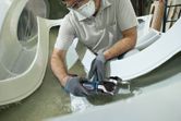 一名佩戴安全設備的人正在使用無線多功能工具切割玻璃纖維。