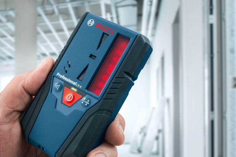 在建建築物中手持雷射接收器的人。.