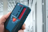 在建建築物中手持雷射接收器的人。