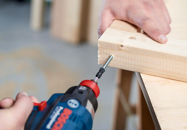 無線電鑽將螺絲旋入兩塊連接的木頭中。.