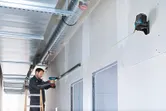 佩戴安全設備的人員使用鑽頭安裝與雷射調平工具對齊的金屬框架。