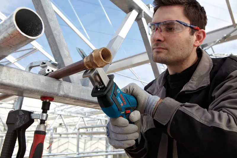 GSA 12V-Li 一名配戴安全設備的人員使用無線往復鋸切割金屬管路。.