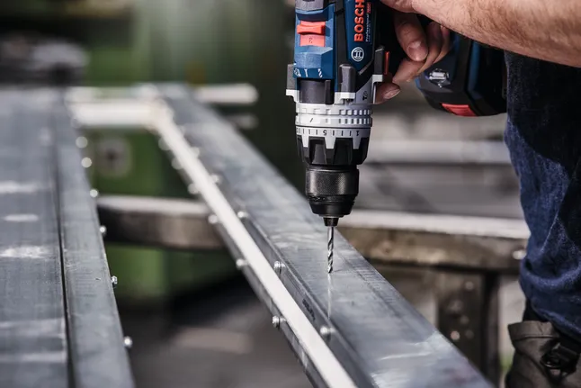 無線電鑽在金屬樑上鑽孔。.