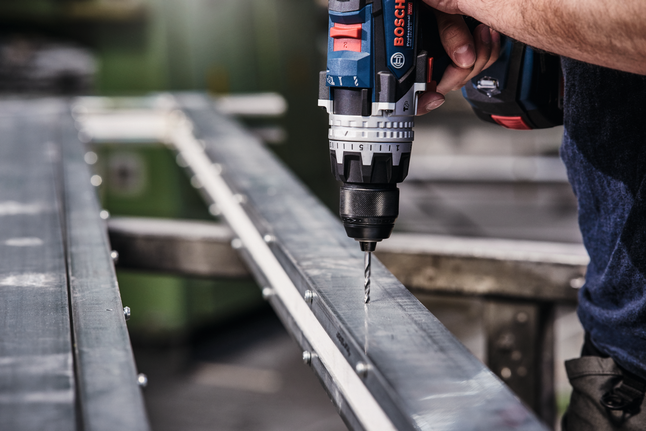 無線電鑽在金屬樑上鑽孔。.