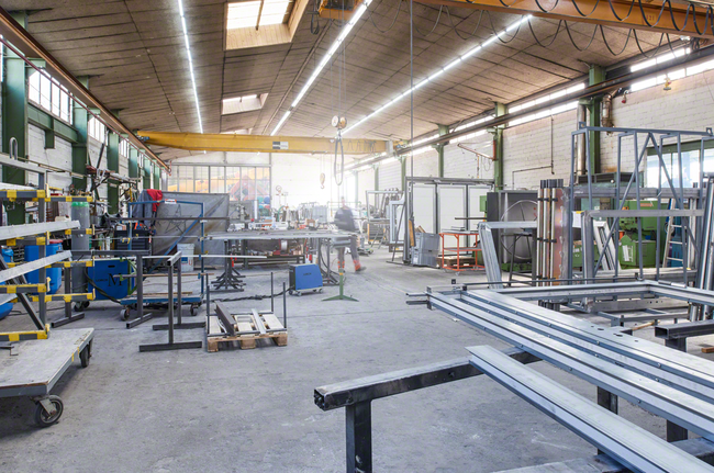 工人穿著安全設備穿過金屬製造車間。.