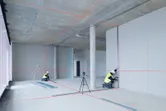 兩名配戴安全設備的人員使用雷射調平工具在建築物內調整乾牆。