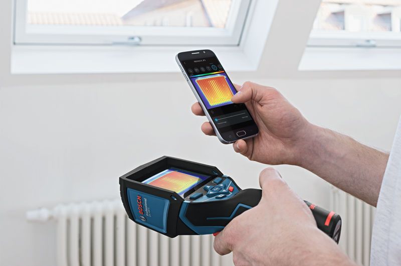 一個人使用熱像儀和智慧型手機在室內查看熱圖像。.