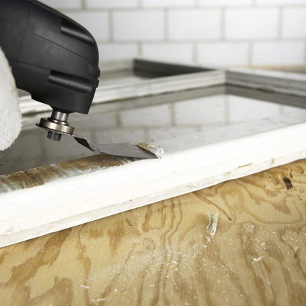 一名穿戴安全裝備的人員使用多功能工具從窗框上移除材料。