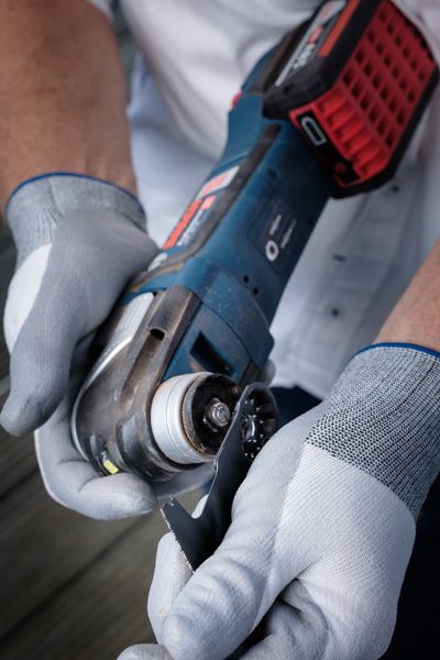 一名配戴安全設備的人員將切割刀片安裝到無線電動工具上。.