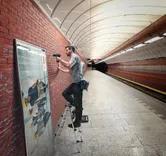 一名男子使用無線電鑽在地鐵站的磚牆上安裝框架。.