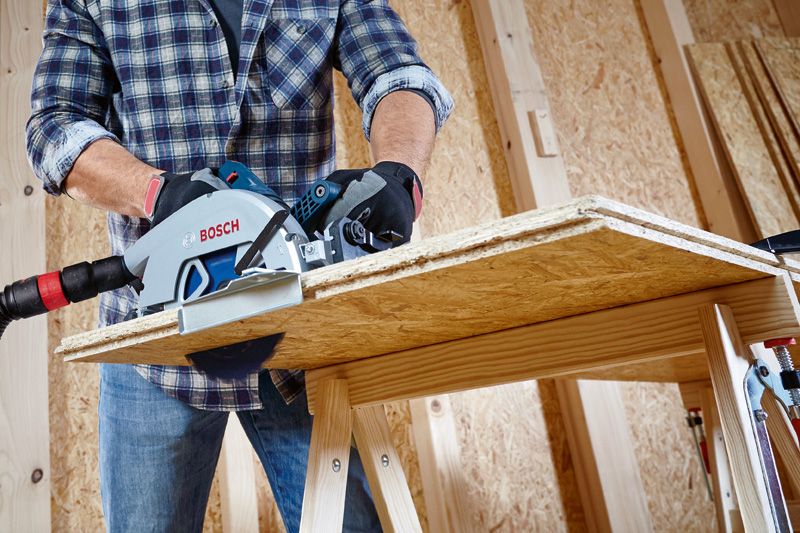 一名佩戴安全設備的人員使用圓鋸切割木板。.