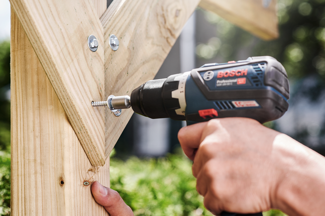 有人正在用無線電鑽將螺絲釘擰入木頭中。