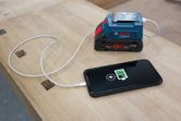 便攜式電池充電器在木製工作台上為智慧型手機供電。