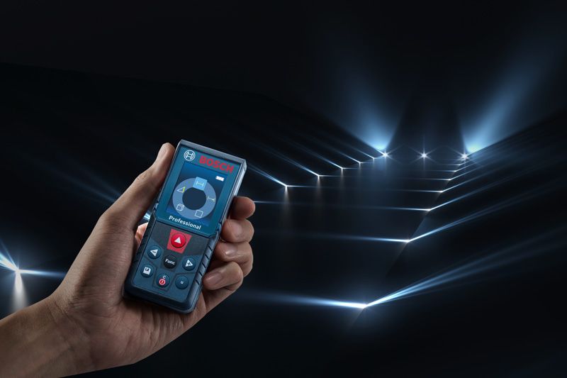 一個人拿著雷射測量儀，在黑暗的房間裡投射出多條測量光束。.