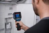 一個人使用熱像儀檢查電氣面板。