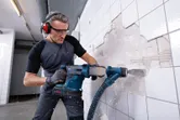 一名穿戴安全裝備的人員使用無線旋轉錘拆除牆磚。
