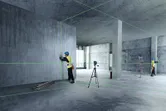 兩名穿著安全設備的工人使用雷射調平工具調整內牆。