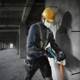 一名配戴安全設備的人員正在使用角磨機切割混凝土。.