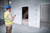 配戴安全設備的人員使用雷射測量儀檢查建築工地的門口尺寸。