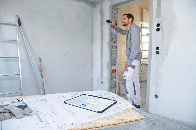 一名工人使用雷射測量儀檢查建築工地的牆壁距離。.