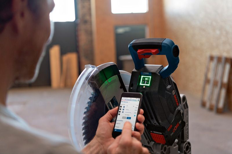 有人使用智慧型手機應用程式調整無線斜切鋸。