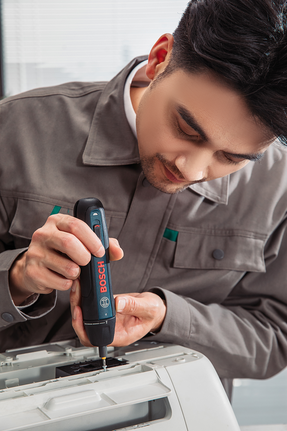 有人正在用無線螺絲起子組裝辦公設備。