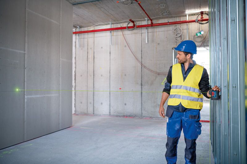 一名配戴安全設備的人員在施工現場使用雷射調平工具。.