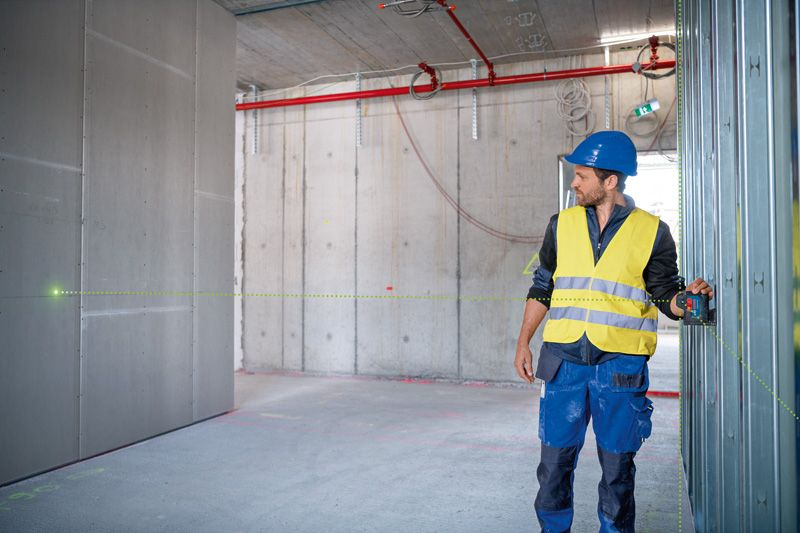 一名配戴安全設備的人員使用雷射調平工具來調整牆體框架。.