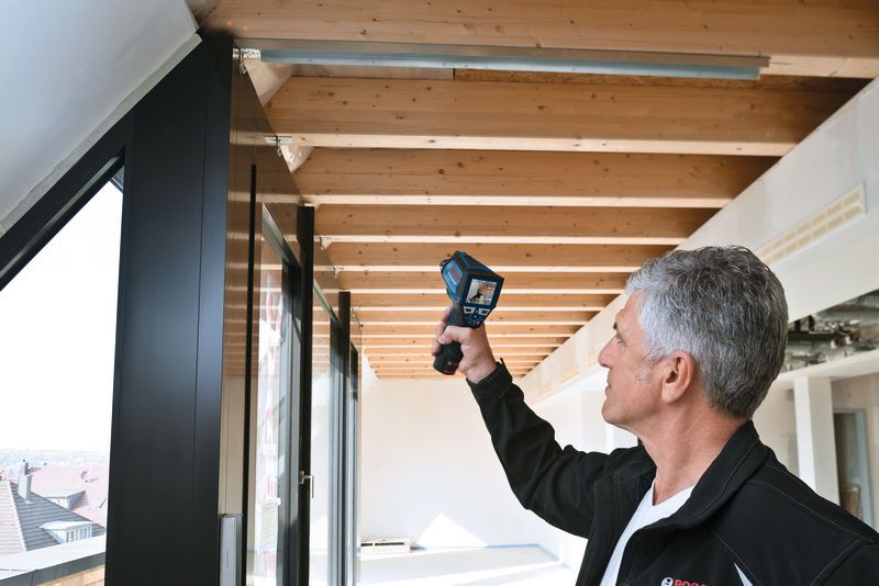 有人使用熱成像儀檢查木製天花板橫樑附近的溫度。