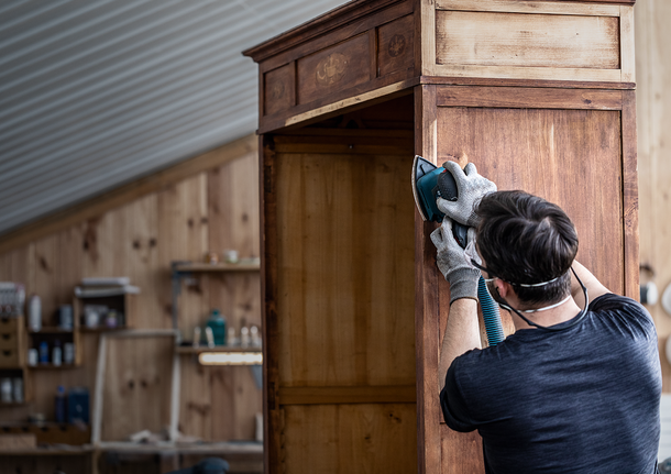 一名工人在車間內配戴安全設備打磨木櫃。