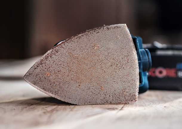 木質表面上的電動工具上安裝的砂磨墊的詳細視圖。