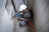 一名佩戴安全設備的人員使用無線熱風槍對橙色電纜進行操作。