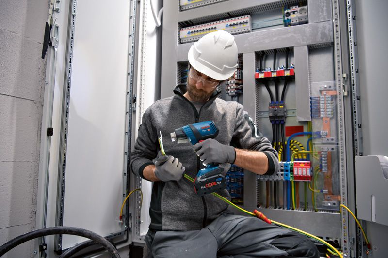 一名佩戴安全設備的人員使用無線熱風槍對電線進行加熱。.