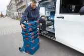 一名工作人員將堆放的工具箱裝載到一輛敞篷貨車旁的推車上。