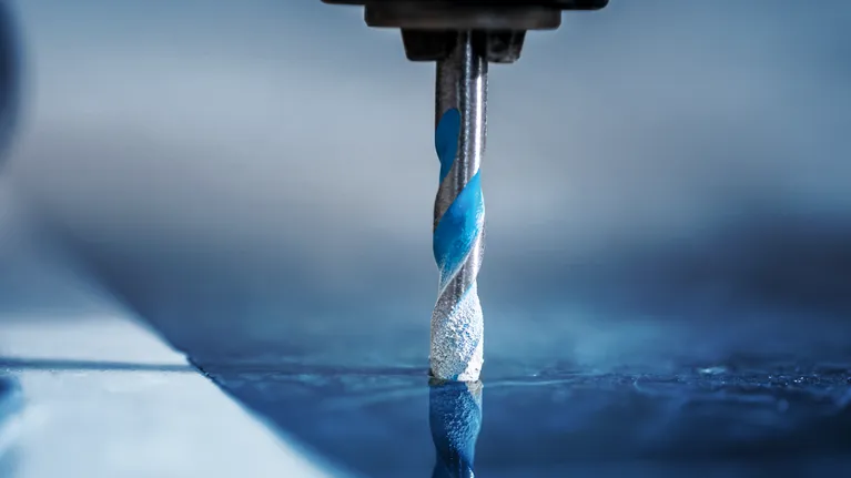 鑽頭在反光瓷磚表面上鑽孔。