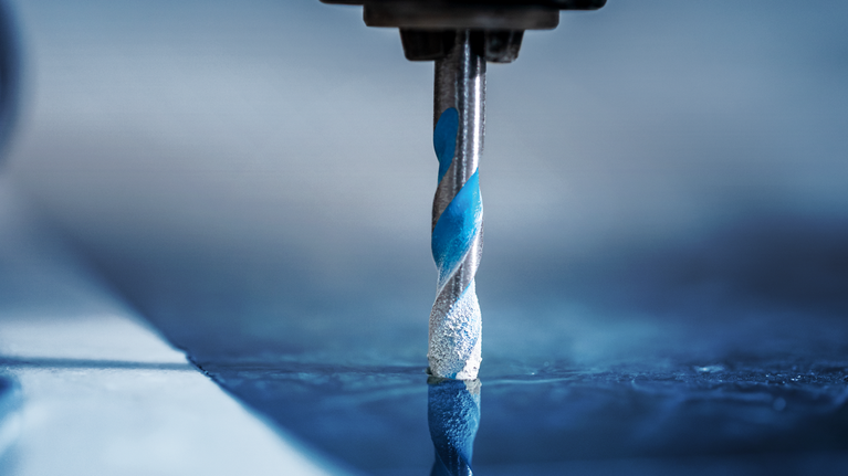 鑽頭在反光瓷磚表面上鑽孔。