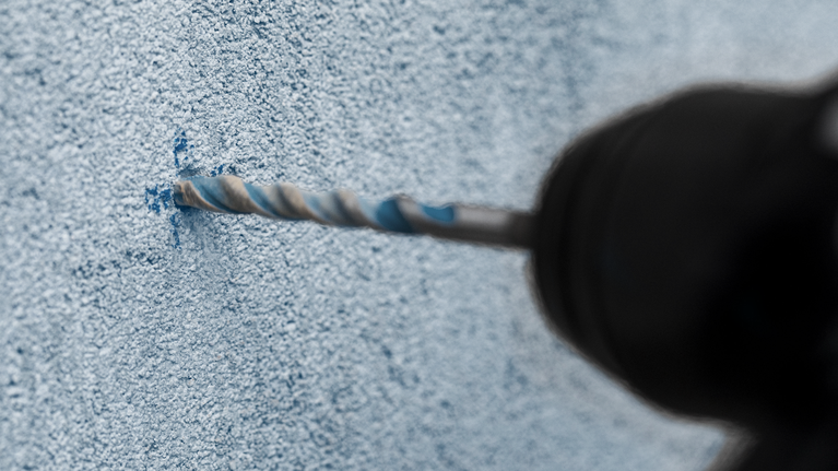 在有紋理的混凝土牆上鑽孔。