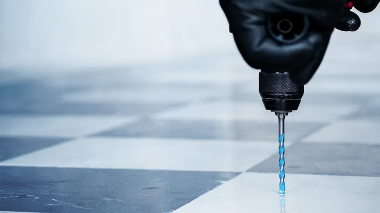 配戴安全設備的人員正在鑽磁磚地板。