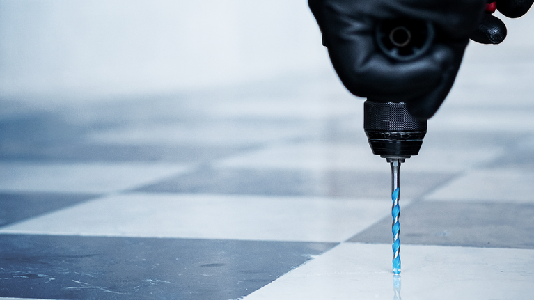 配戴安全設備的人員正在鑽磁磚地板。