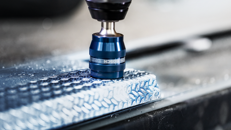 金屬鑽頭在紋理鋁表面上鑽出一個孔。