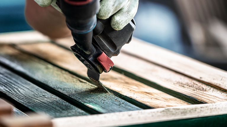 配戴安全設備的人員使用砂光機打磨木質表面。